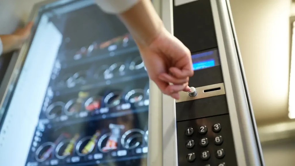 Low perspective image of a user making a selection from a vending machine stocked with various snacks and drinks