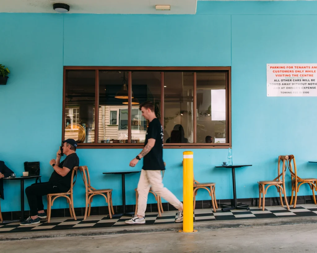A Milkmen Supply Co. delivery driver walks past a Brisbane cafe storefront, marking the handover to Kellys Distributors